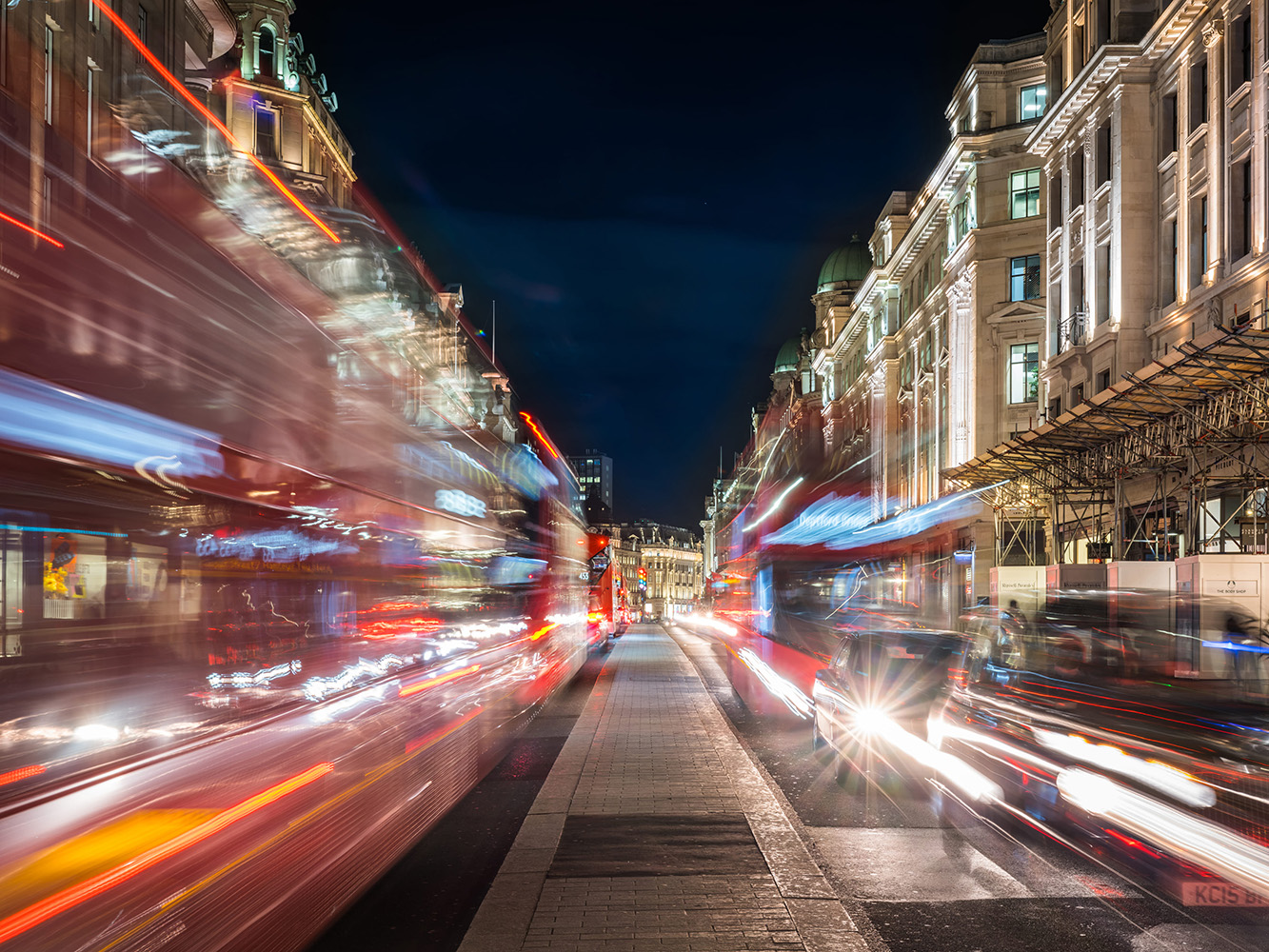 Image of London street at night with buses and taxis in motion